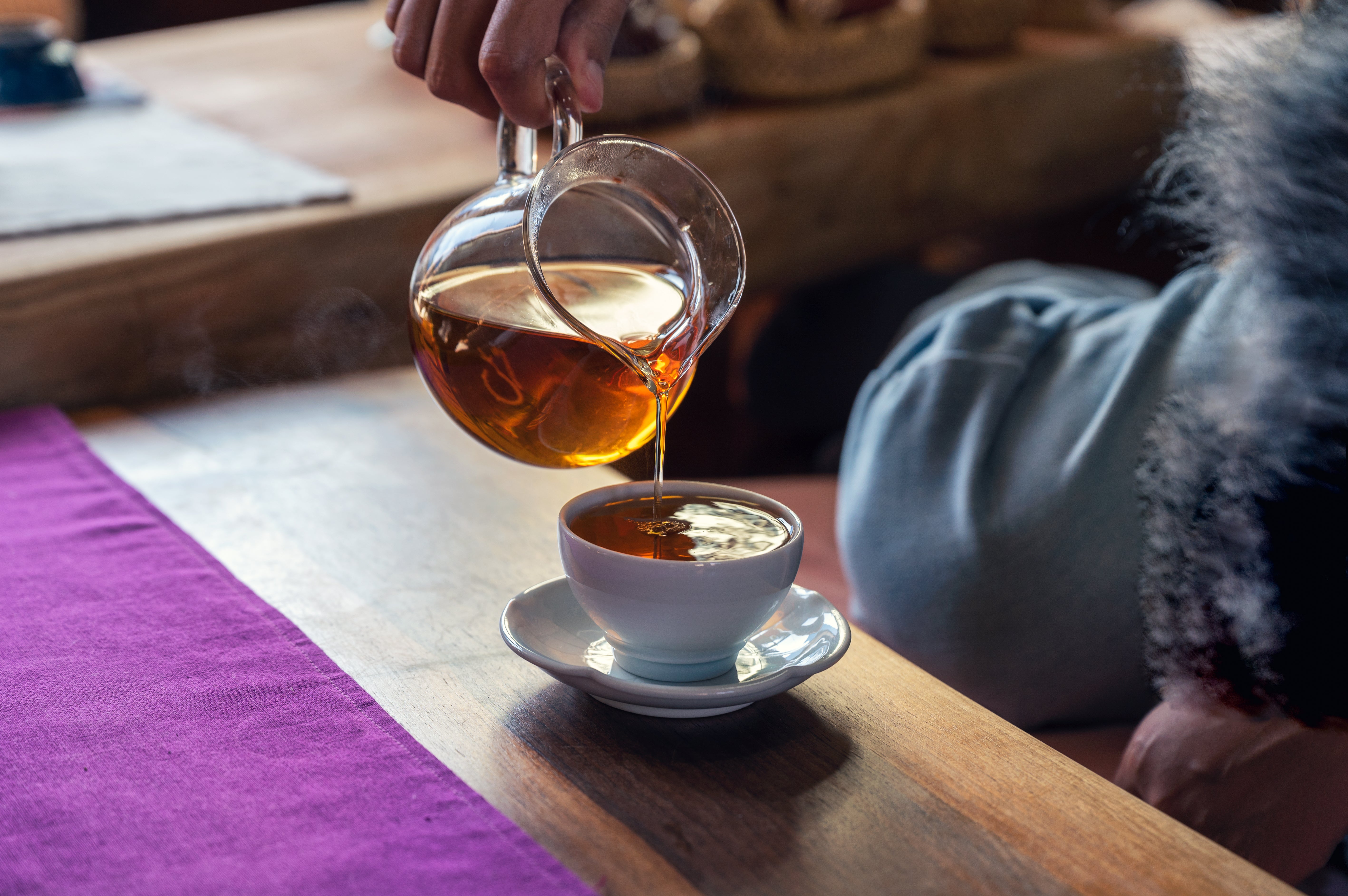 Hot Krocus & Co. tea poured from a glass jug into a white teacup