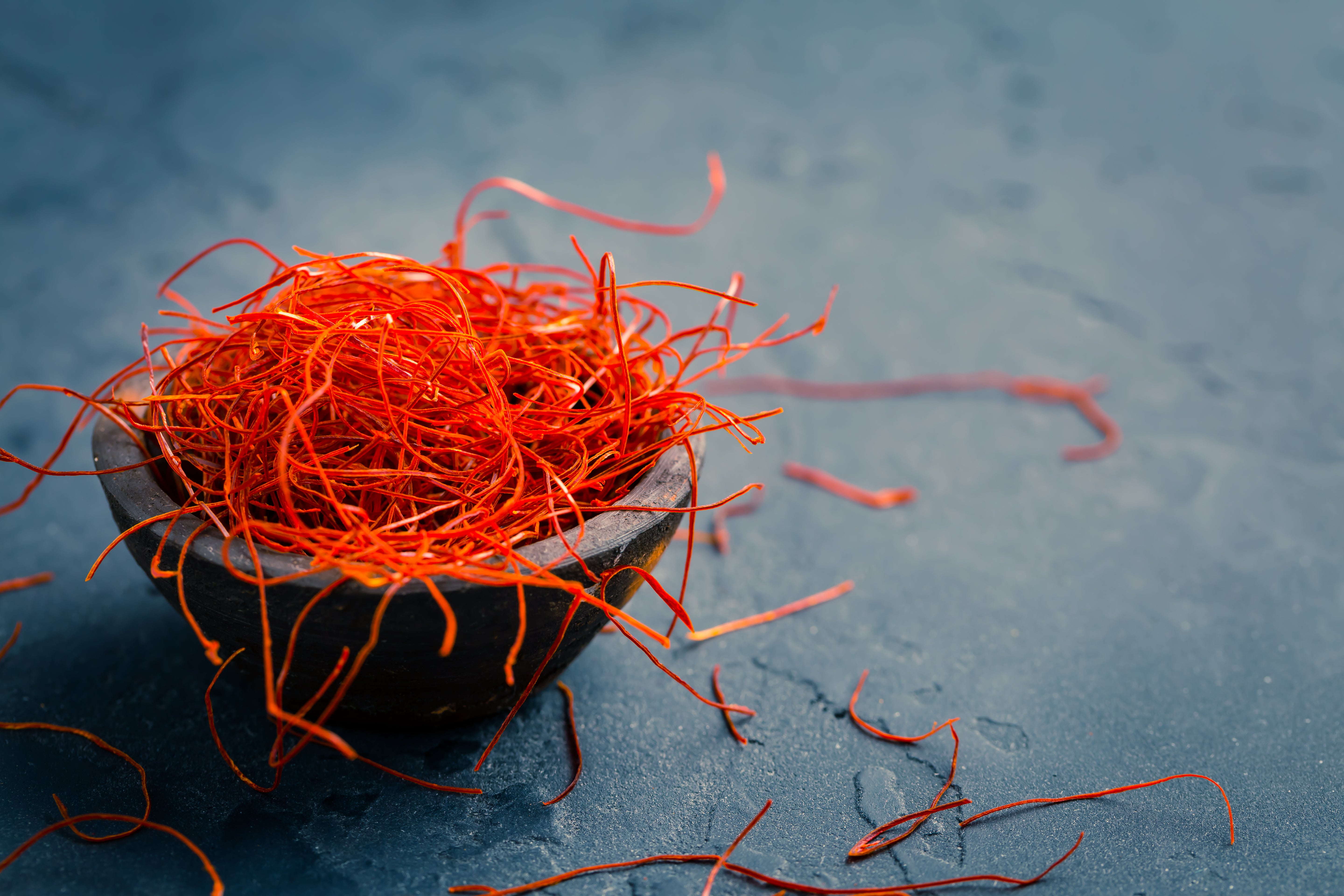 Hand-picked Greek saffron threads in a dark bowl on slate surface, used in Krocus & Co. tea blends