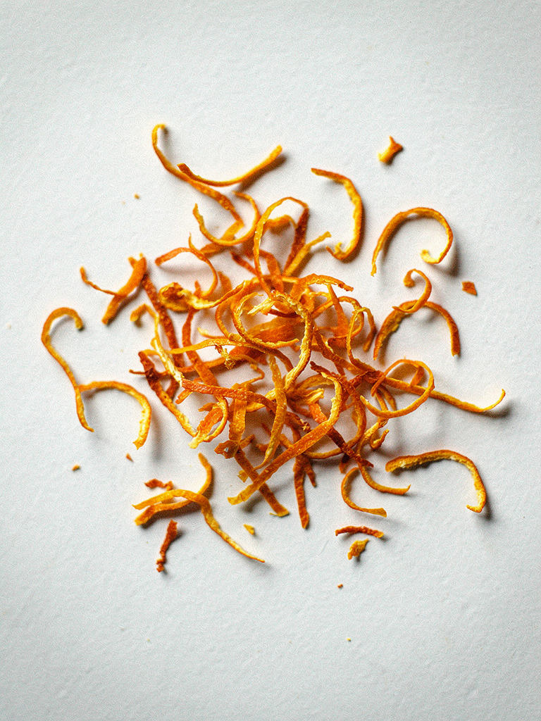 Orange zest strands on a light surface, an ingredient in Krocus & Co. Cinnamon & Clove herbal tea